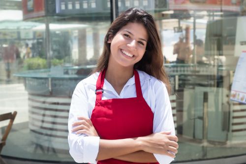 Junge Kellnerin vor dem Restaurant